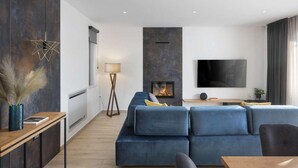 En moderne stue med en hjørnesofa, pejs, fladskærms-tv og minimalistisk indretning.