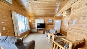 A cozy wooden cabin interior with a sofa, a television, and a fireplace. - Cabin 9 Lakefront Family Resort (Hines)