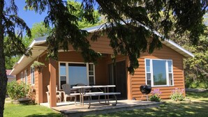 A small, single-story house with a covered patio, a barbecue grill, and a table with chairs. - Cabin 9 Lakefront Family Resort (Hines)