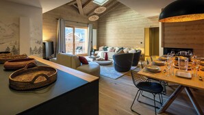 A modern interior with a wooden ceiling, a dining area with a table set for a meal, and a cozy seating area with a sofa and chairs.
