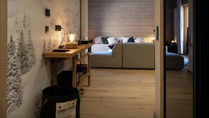 A cozy room with a wooden desk, a bed with patterned pillows, and a wall with a nature-themed mural.
