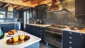 A modern kitchen with dark cabinetry, a stainless steel stove, and a tiled backsplash.
