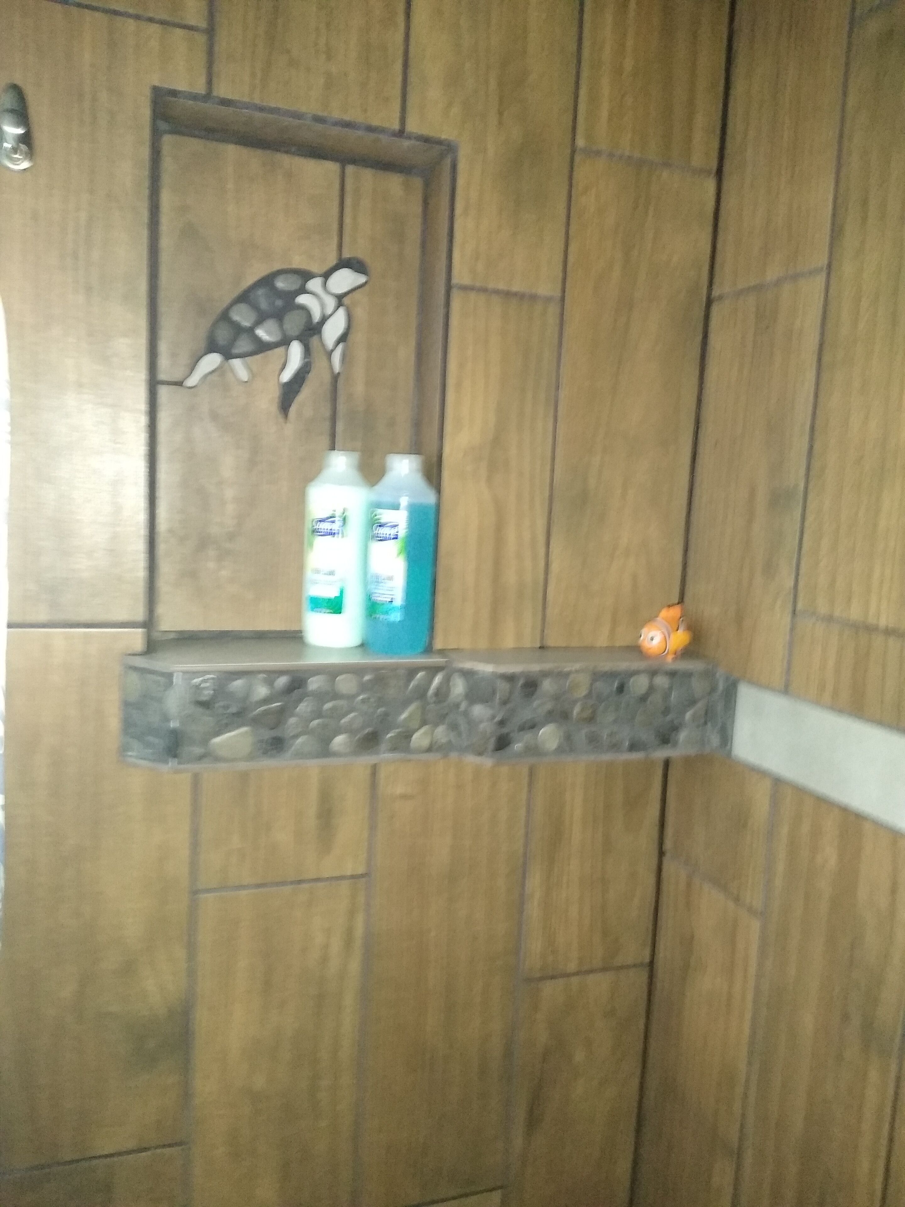 Une salle de bain avec un mur en bois, une étagère contenant des articles de toilette et une tortue décorative.