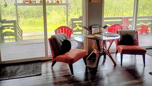 A room with a glass door leading to an outdoor deck, a round table with chairs, and a small table with a candle.