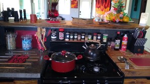 A kitchen with a stove, pots, and a variety of spices and condiments on the counter.
