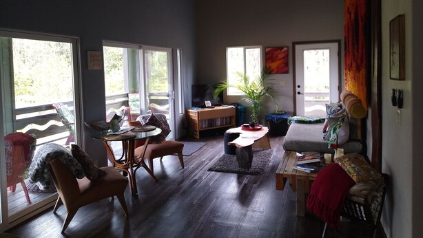 A spacious living room with a large window, a ceiling fan, and a wooden coffee table.