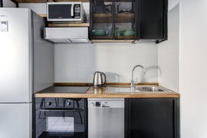 Cocina compacta con microondas, estufa, fregadero y lavavajillas.