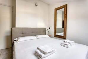 Una habitación de hotel con una cama, un espejo grande y toallas dobladas con cuidado.
