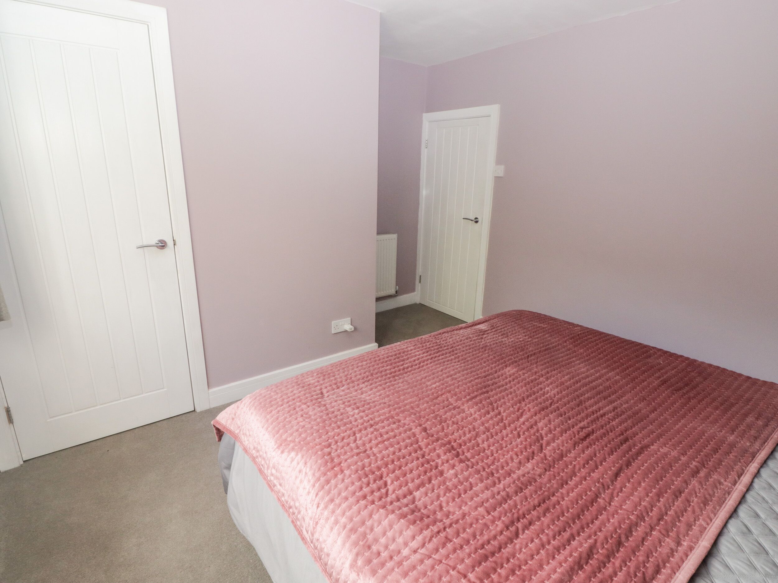 A bedroom with a bed, a white door, and a white closet.