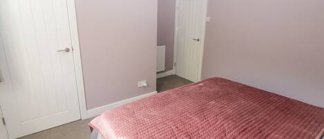 A bedroom with a bed, a white door, and a white closet.