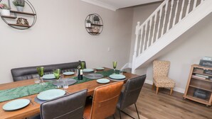 A dining area with a wooden table set for six, surrounded by leather chairs. - Golygfa Bryn (Porth)