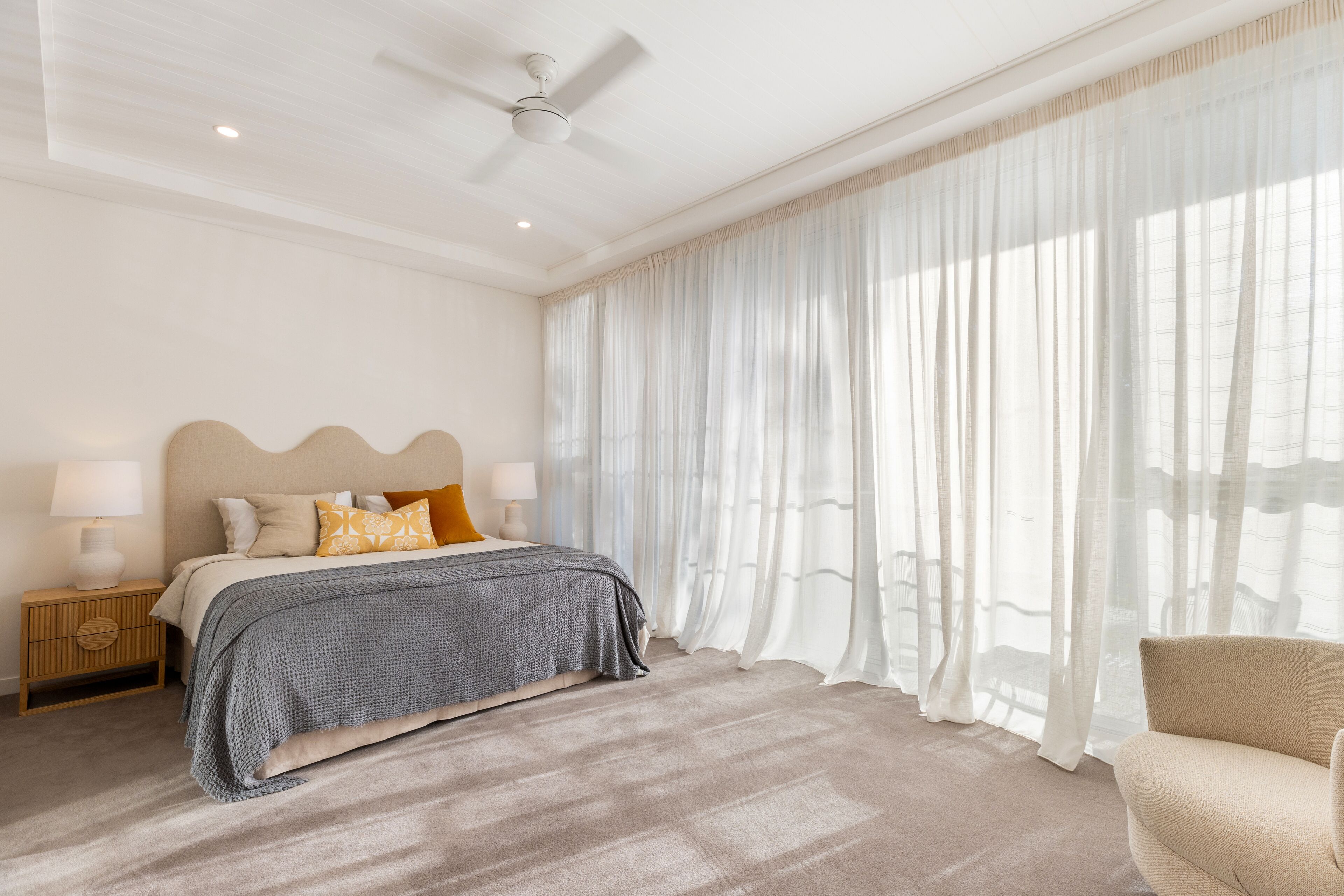 A bedroom with a bed, nightstand, lamp, and a ceiling fan.