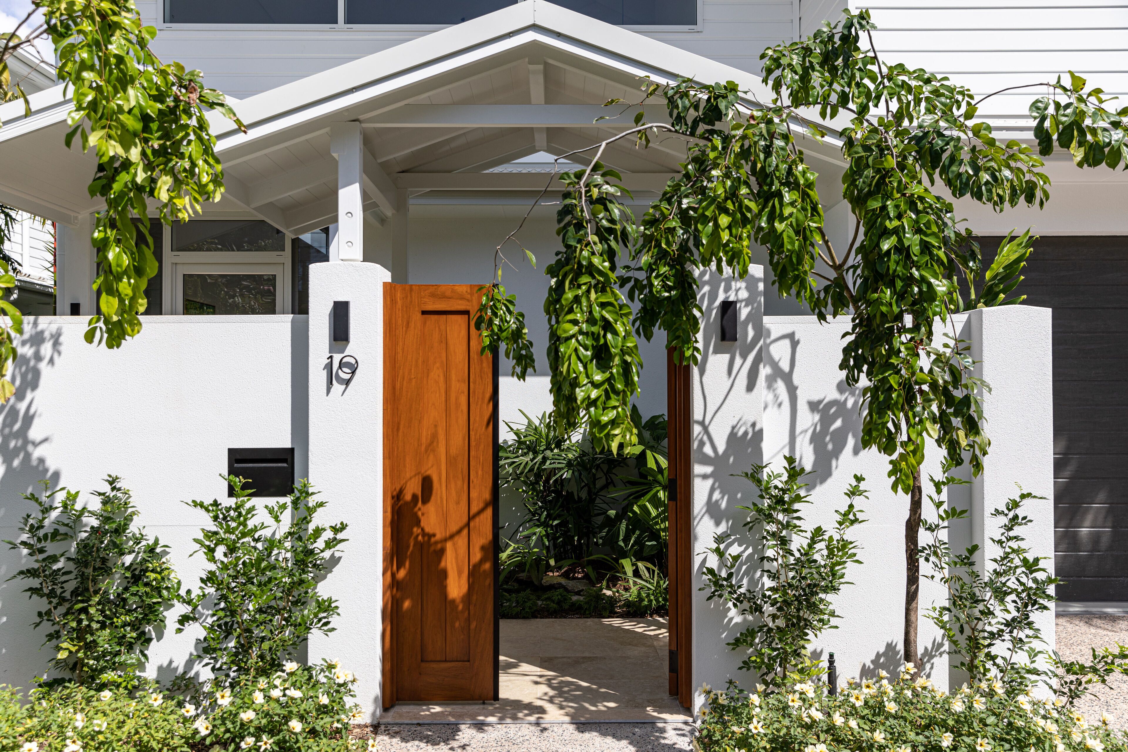 Una casa moderna con una porta in legno, pareti bianche e un ingresso coperto.