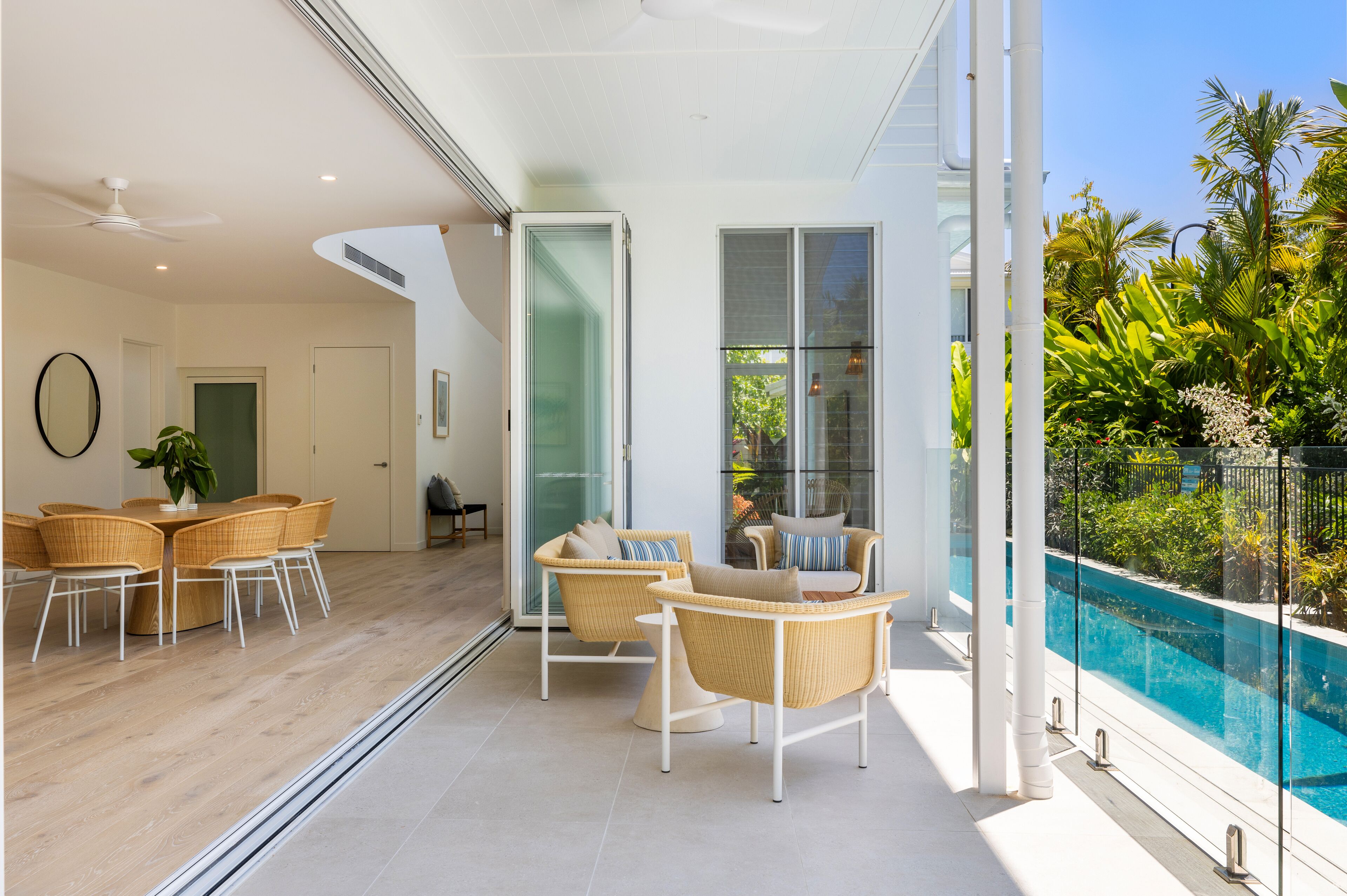 Interior moderno com área de refeições, assentos perto de um muro de vidro e vista para a piscina.
