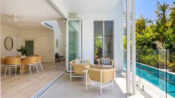 Interior moderno com área de refeições, assentos perto de um muro de vidro e vista para a piscina.