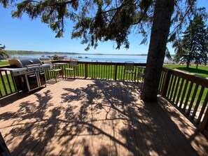 Une terrasse en bois avec un barbecue, des chaises et une vue sur un lac.