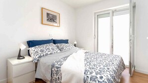 Une chambre à coucher comprenant un lit, une table de chevet, une lampe, un tableau encadré au mur et une porte coulissante.