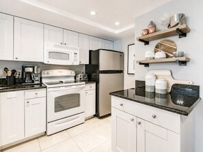 Una cocina moderna con armarios blancos, electrodomésticos de acero inoxidable y encimera de granito.