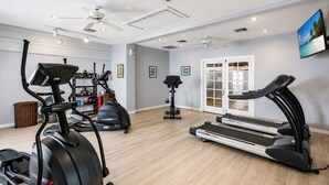 Une salle de sport à domicile équipée de tapis de course, d’un vélo elliptique et d’un vélo d’appartement.