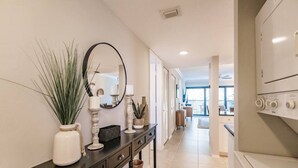 A modern hallway with a black console table, a mirror, and decorative items. - Park Shore Resort-Top Floor BLDGC #221*Peaceful* (Park Shore Resort)