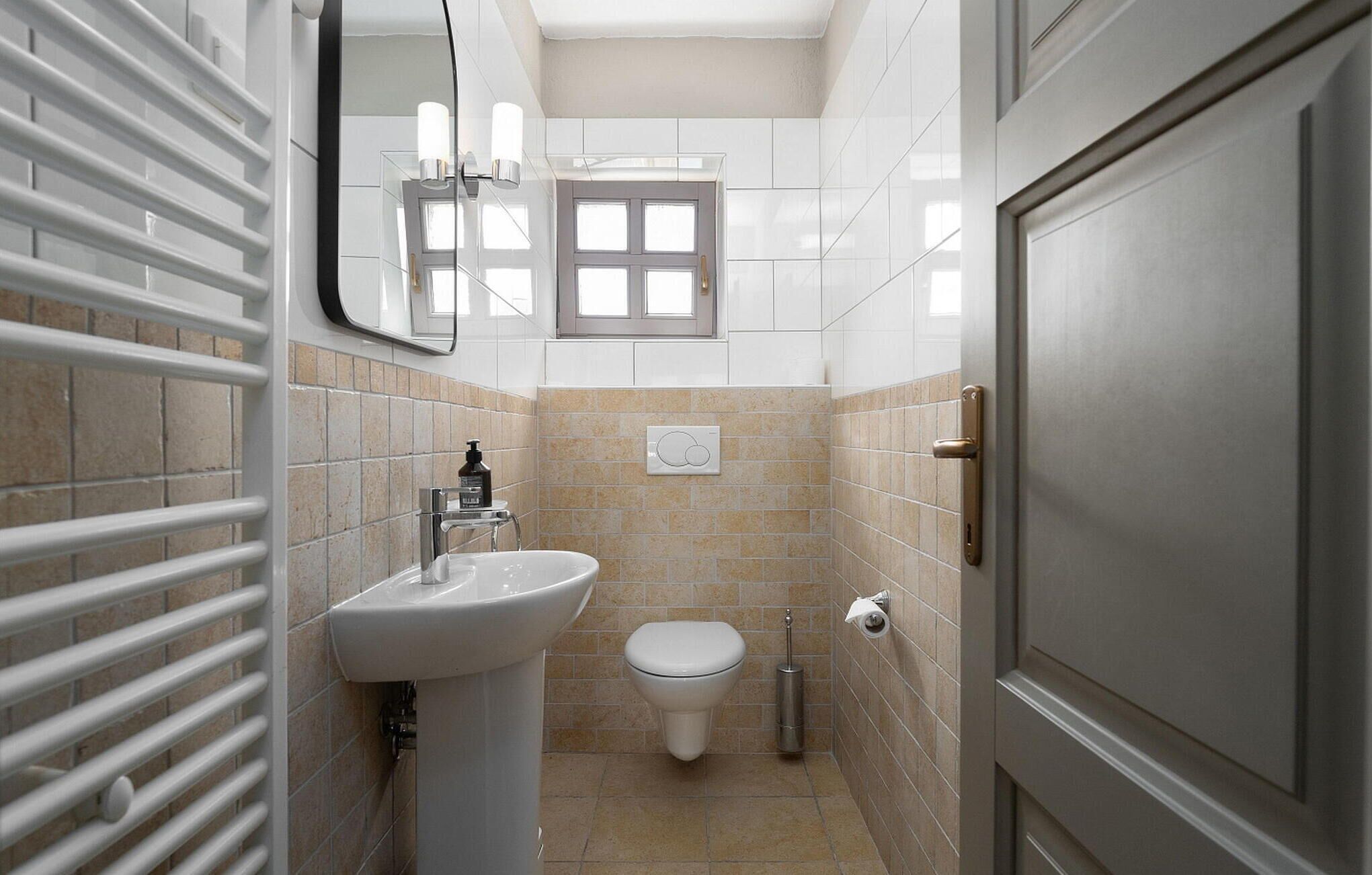 Un baño pequeño con un lavamanos blanco, inodoro y una ventana sobre el inodoro.