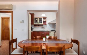 A compact kitchen with wooden cabinets, a dining table with chairs, and a pendant light. - Lovely apartment in Rovinj with WiFi (Rovinj)
