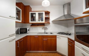 A compact kitchen with wooden cabinets, a microwave, a sink, and a stove. - Lovely apartment in Rovinj with WiFi (Rovinj)