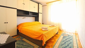 A bedroom with a bed, a nightstand, a wardrobe, and a window with curtains.