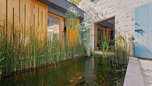 A tranquil indoor pond with koi fish, surrounded by tall grasses and a wooden fence. - Gorgeous home in Porec (Porec)