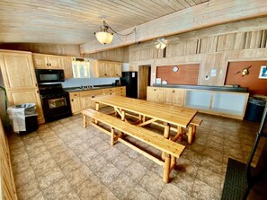 A rustic kitchen with wooden cabinets, a large wooden table, and a built-in oven. - Cabin 11 Lakefront Family Resort (Hines)