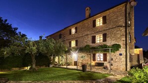 A stone building with a covered outdoor seating area, a well-maintained lawn, and a clear night sky.
