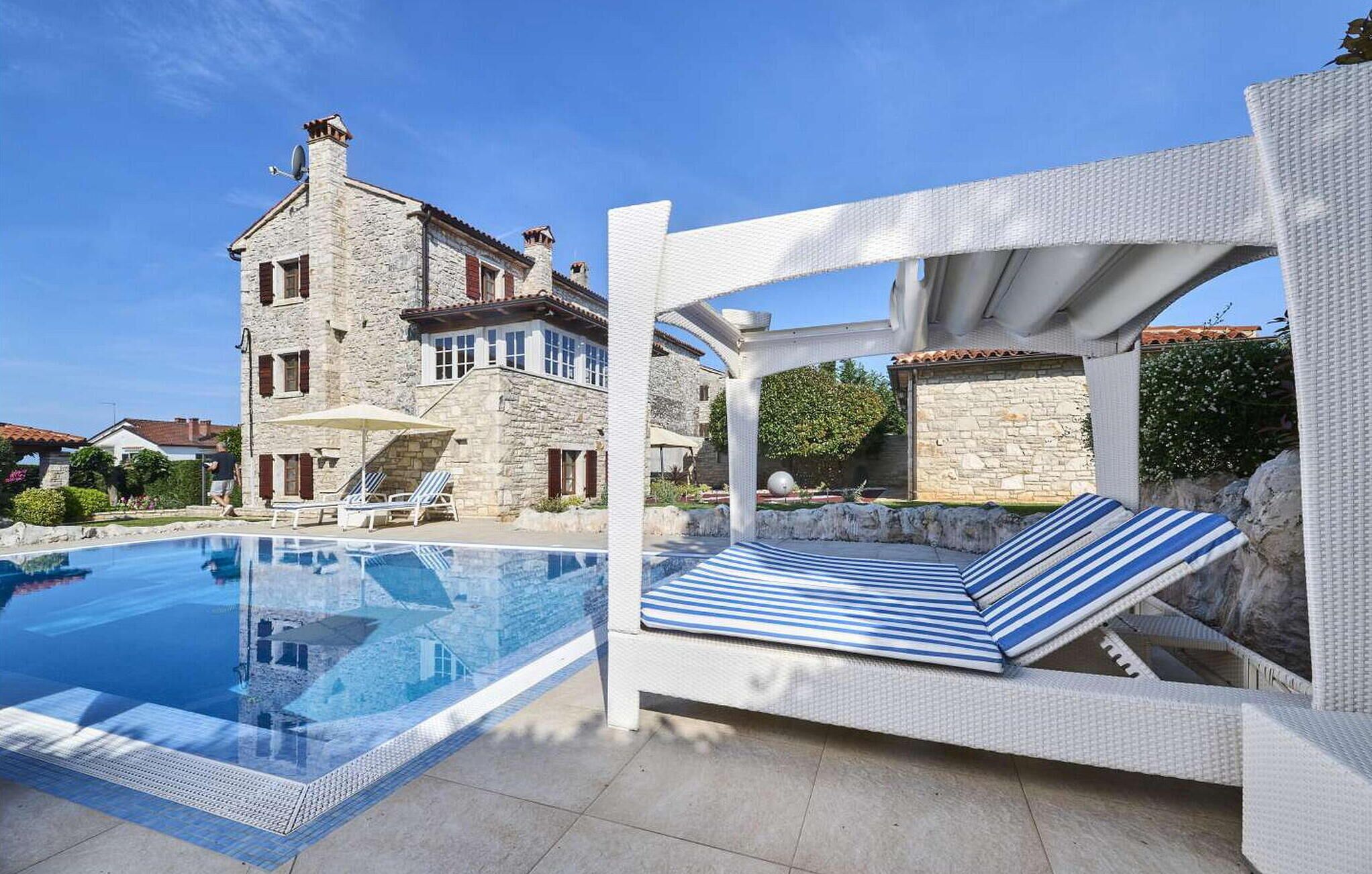 A pool area with a lounge chair and a stone building in the background.