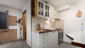 A modern kitchen with white cabinetry, a wooden countertop, a built-in stove, and a brick accent wall.