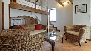 A cozy room with a wicker sofa and armchair, a glass coffee table, and a staircase leading to an upper level. - 2 bedroom beautiful home in Labin (Labin)