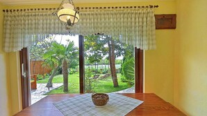 A dining table with a placemat and a woven basket, set against a yellow wall with a view of a garden through a glass door. - 2 bedroom beautiful home in Labin (Labin)