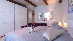 Een slaapkamer met een bed, nachtlampjes, een dressoir en een spiegel.