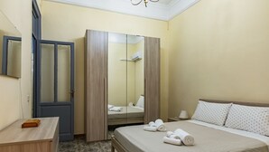 A hotel room with a bed, a wardrobe, a desk, and a mirror.