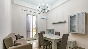 A dining area with a table, chairs, a chandelier, a sofa, and a cabinet with glass doors.