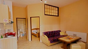 A compact room with a kitchenette, a bed, a sofa, and a small table. - Holiday apartment with air conditioning (Fažana)