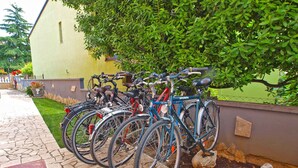A row of bicycles parked against a wall with a stone pathway leading to a building. - Holiday apartment with air conditioning (Fažana)