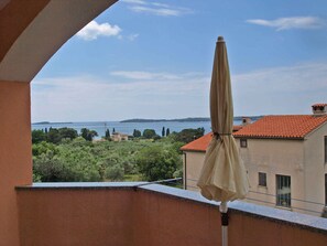 A balcony with a view of a body of water and greenery. - Holiday apartment with balcony (Fažana)