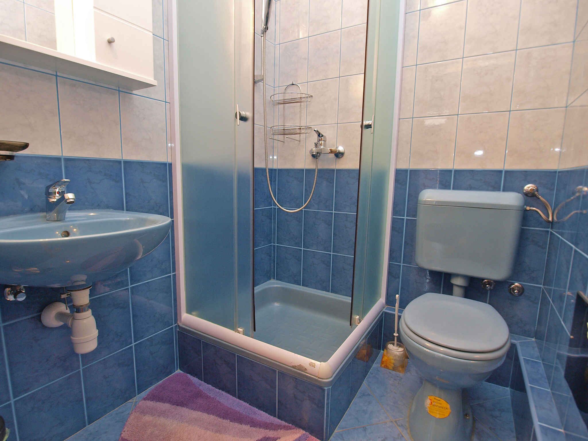 A bathroom with a glass-enclosed shower, a sink, and a toilet.