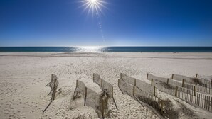 A beach with a clear sky and the sun shining brightly.