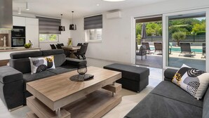 Una sala moderna con un conjunto de sofás, una mesa de centro de madera y un comedor con sillas y una mesa.
