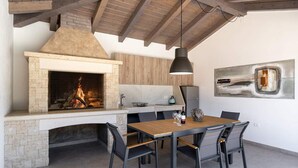 Una cocina moderna con chimenea de piedra, vigas de madera en el techo y un comedor con mesa y sillas.