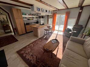Un vaste espace de vie comprenant un canapé, une table basse et une cuisine dotée de meubles en bois et d’un îlot central.
