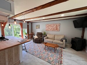 A modern kitchen with a dining area, a sofa, and a television.