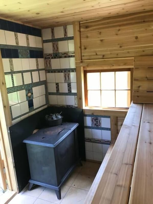 A compact kitchen with a tiled backsplash, a small stove, and a window providing natural light.
