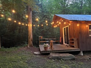 A rustic cabin with a wooden deck, surrounded by trees. - The Creek Cabin at Sky Hollow, The Creek Cabin at Sky Hollow (Rochester)