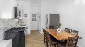 Une cuisine moderne avec des meubles blancs, une cuisinière noire et une table à manger en bois, accompagnée de chaises.